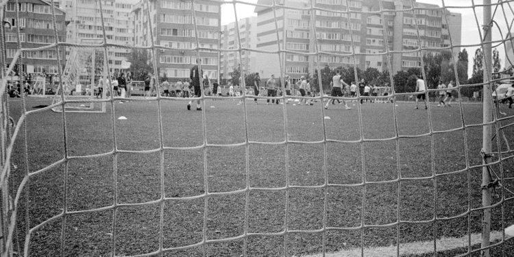 Imagem retrô em preto e branco da rede de um gol e um campo de futebol